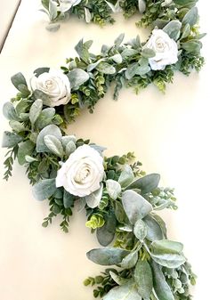 some white flowers and green leaves are arranged in the shape of an oar on a table