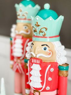 three wooden nutcrackers with green crowns and blue eyes are standing next to each other