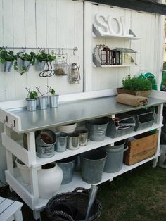 an outdoor kitchen with pots and pans on the shelf next to potted plants