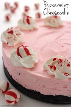 a pink cake with white and red icing on it's top, surrounded by candy canes