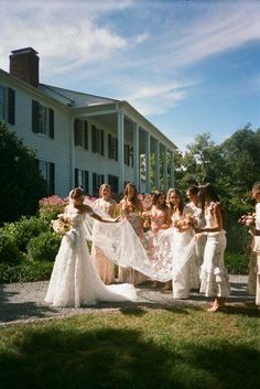 a group of women standing next to each other in front of a house