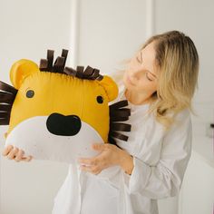 a woman is holding a pillow with a stuffed animal on it's face and the head of a lion