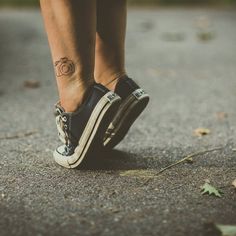 a woman's foot with a tattoo on her left leg and the bottom part of her shoe