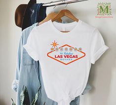 a t - shirt with the word las vegas printed on it hangs next to some jeans