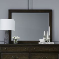 a large mirror sitting on top of a dresser next to a lamp