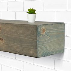 a potted plant sitting on top of a wooden shelf next to a white brick wall