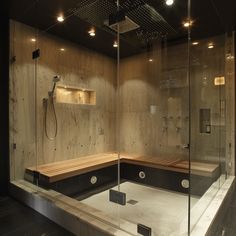 a bathroom with a large glass shower and wooden bench in the corner, along with built - in shelving