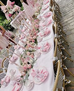 a long table with pink flowers and plates on it