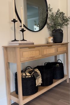 a wooden table topped with baskets under a mirror