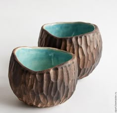 two wooden bowls sitting next to each other on a white surface with one bowl in the middle