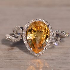 The 33rd Avenue: Checkerboard Citrine And Natural Diamond Ring In White Gold. This Ring Showcases A Pear-Shaped Checkerboard-Cut Natural Citrine At The Center, Surrounded By A Halo Of Round-Cut Natural Diamonds. Completing The Look Is A Scrolled Bypass-Style Shank, Also Adorned With Round-Cut Natural Diamonds. Crafted In 14 Karat White Gold, The Ring Is Currently A Finger Size 7 But Can Be Adjusted To Any Finger Size For An Additional Charge Upon Request, Ensuring A Customized And Perfect Fit. Natural Diamond Ring, Natural Citrine, Womens Jewelry Rings, Pear Shaped, Citrine, Yellow White, Round Cut, Natural Diamonds, Gold Color