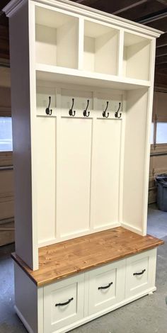 a white bench with two drawers and three hooks on the top, in a garage