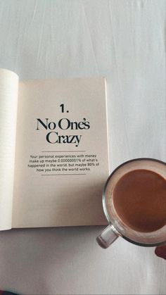 a person holding a cup of coffee next to an open book with the title, no one's crazy