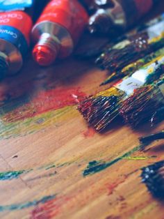 some paintbrushes are sitting on a table with different colors and shapes in them