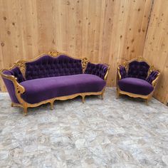 two purple couches sitting next to each other in front of a wood paneled wall