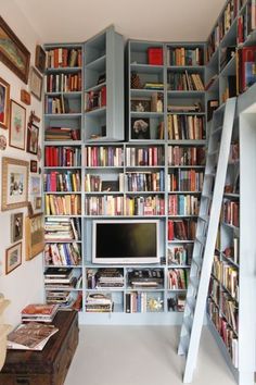 a bookshelf filled with lots of books next to a tv and ladders