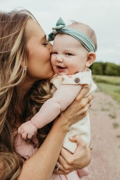 a woman holding a baby in her arms and kissing it's face on the cheek