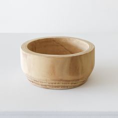 a wooden bowl sitting on top of a white table