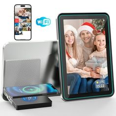 an electronic photo frame with a christmas scene on the screen next to it and a phone