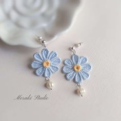 a pair of blue and white crocheted flower earrings with pearls on the end