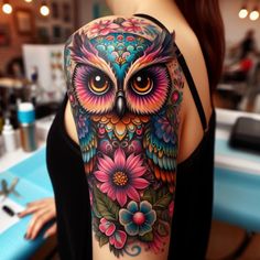 an owl tattoo on the back of a woman's shoulder, with flowers around it