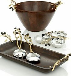 an assortment of silverware and spoons on a wooden serving tray with gold accents