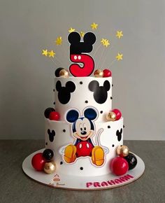 a three tiered cake decorated with mickey mouse and gold stars on the top layer