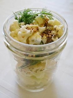 a glass jar filled with food sitting on top of a white tablecloth covered table