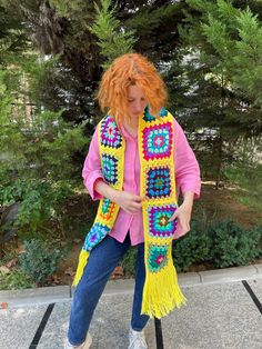 a woman with red hair is wearing a yellow crocheted scarf and blue jeans