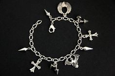 A collection of silver plated punk rock themed charms have been dispersed around a shimmering silver plated bracelet chain in this handmade charm bracelet. This rock n roll charm bracelet is then completed with a lobster clasp and a 1/2 inch of chain at the end for adjustable sizing. Charms in this bracelet include a winged skull charm, winged heart charm, two cross charms, three long spike charms, and four short spike charms. ● Sizing ● To determine your bracelet size, do a snug measurement of Handmade Charm Bracelets, Winged Skull, Winged Heart, Silver Plated Bracelet, Bracelet Chain, Themed Jewelry, Handmade Charms, Cross Charms, Bracelet Silver