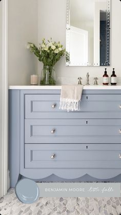 the bathroom is painted in blue and has white trim on the drawers, along with a large mirror over the sink