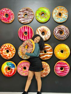 a woman standing in front of a display of doughnuts