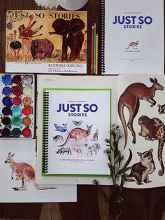 several children's books are displayed on a wooden table with flowers and other items