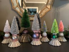 christmas trees are lined up on a table in front of a mirror and other decorations