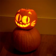 a pumpkin carved to look like a cat sitting on top of another pumpkin with its eyes open