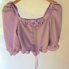 This Brand New Top Can Be Styled So Many Different Ways. It Is Lined In The Front And Is A Beautiful Lilac Color. It Has Ruffle Details And Can Be Worn Off The Shoulders. It Has A Pull Strings In The Front. It Is A Cropped Style. Size Small Armpit To Armpit 15 Inches Length 9.5 Inches 355 Light Lilac, Lilac Color, Shein Tops, New Top, Cropped Style, Off Shoulder Blouse, Off The Shoulder, Lilac, Off Shoulder