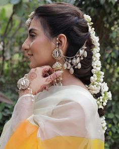 a woman in a yellow and white sari with jewelry on her neck, looking off to the side