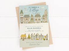 a greeting card with an illustration of a town on the front, and it says it takes a village