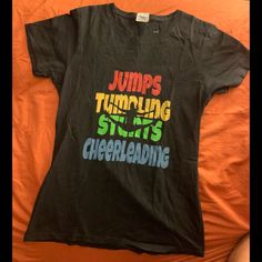 Cheerleading Short Sleeve T-Shirt . In Excellent Condition. Never Worn Sporty Graphic Print T-shirt For Cheerleading, Black Graphic Print Top For Cheerleading, Black Short Sleeve Tops For Cheerleading, Sporty T-shirt For Cheerleading With Screen Print, Sporty Cheerleading T-shirt With Screen Print, Black Top With Letter Print For Cheerleading, Black Crew Neck T-shirt For Cheerleading, Cheerleading Crew Neck Top With Screen Print, Crew Neck T-shirt With Text Print For Cheerleading