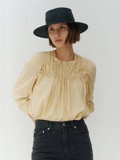 This is REMPLACEMENT’s blouse features a cool and soft touch with shirring as the focal point. The double lines of shirring create an elegant shoulder line and allow for additional shirring to be adjusted according to individual body shapes. - Ideal for daily wear- Can be paired with various bottoms for versatile styling- Japanese directly imported double-sided velvet ribbon, dyed to match the fabric color, adds a detailed touch Chic Billowy Tops With Smocked Cuffs, Chic Long Sleeve Smocked Top With Ruched Detail, Chic Long Sleeve Ruched Smocked Top, Spring Blouse For Workwear With Elastic Shoulders, Spring Workwear Blouse With Elastic Shoulders, Spring Billowy Ruched Blouse, Workwear Long Sleeve Blouse With Elastic Shoulders, Chic Blouse With Smocked Back And Billowy Fit, Billowy Long Sleeve Ruched Top