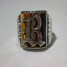 "Another cool ring for the guys! Bold ring that will make a statement. This is a 10k white gold men's ring. It will fit approx. a size 8.5 so a woman could wear as well. Sizable and good weight at 6.6 grams. Nice fan detailing on the sides and a scalloped edge on top and bottom of frame. Bezel set is a large Tigers Eye gemstone. Stone is approx. 3/4 inches long and 5/8 inch wide. Center is set with a script Gothic letter. Not sure what the letter is, font is a bit unusual, but I would guess a le Formal White Gold Jewelry With Initials, Silver Formal Jewelry With Initials, Silver Rectangular Jewelry For Wedding, Vintage Sterling Silver Jewelry With Initials, Antique Silver Personalized Jewelry, Antique Personalized Silver Jewelry, Antique Personalized Jewelry For Formal Occasions, Antique Personalized Formal Jewelry, Vintage Wedding Jewelry With Initials