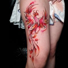 a woman's thigh with a colorful bird tattoo on it