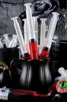 a black vase filled with red and white candles next to other items on a table