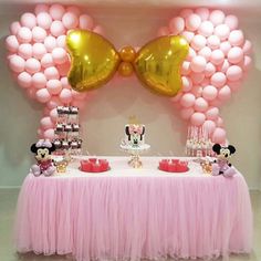 a table topped with lots of balloons and minnie mouses on it's head