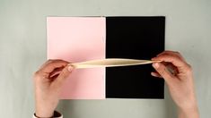 a person holding a toothbrush in front of a pink and black square piece of paper