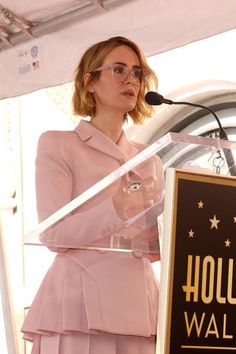 a woman standing at a podium in front of a sign with hollywood walk of fame written on it