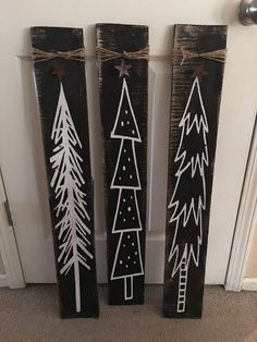 three christmas trees painted on wooden planks in front of a door