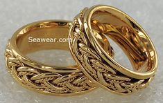 two gold wedding rings sitting on top of each other