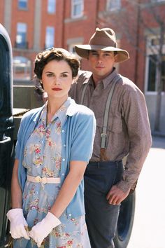 two people standing next to an old truck