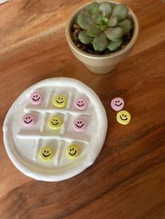 a small potted plant sitting next to a white plate with smiley faces on it